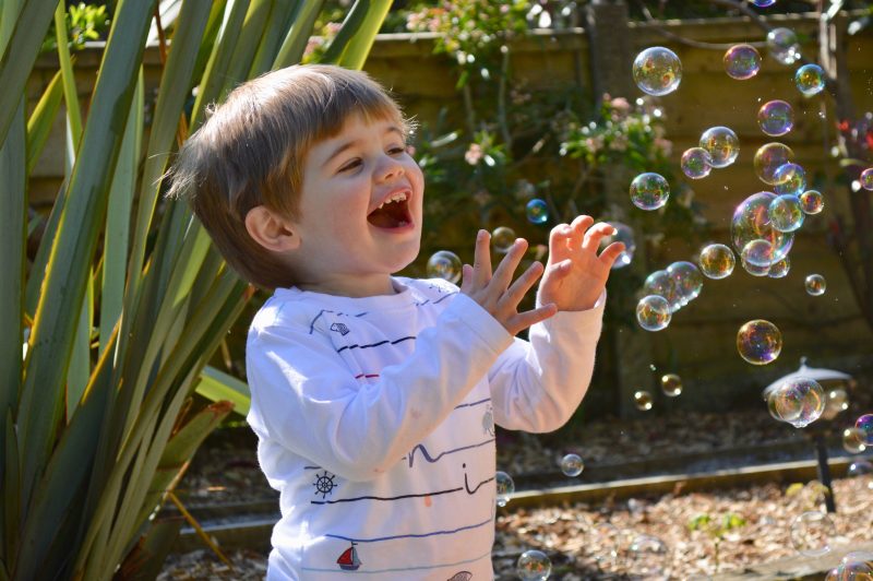 toddler playing in the garden with bubbles